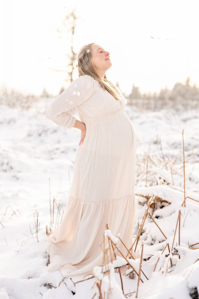 Schwangere steht in schöner Schneelandschaft