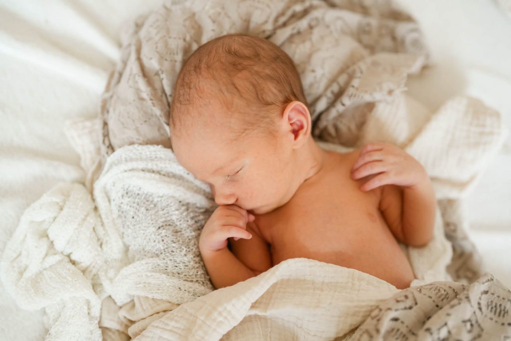 schlafendes Neugeborenes liegt eingekuschelt in Decken