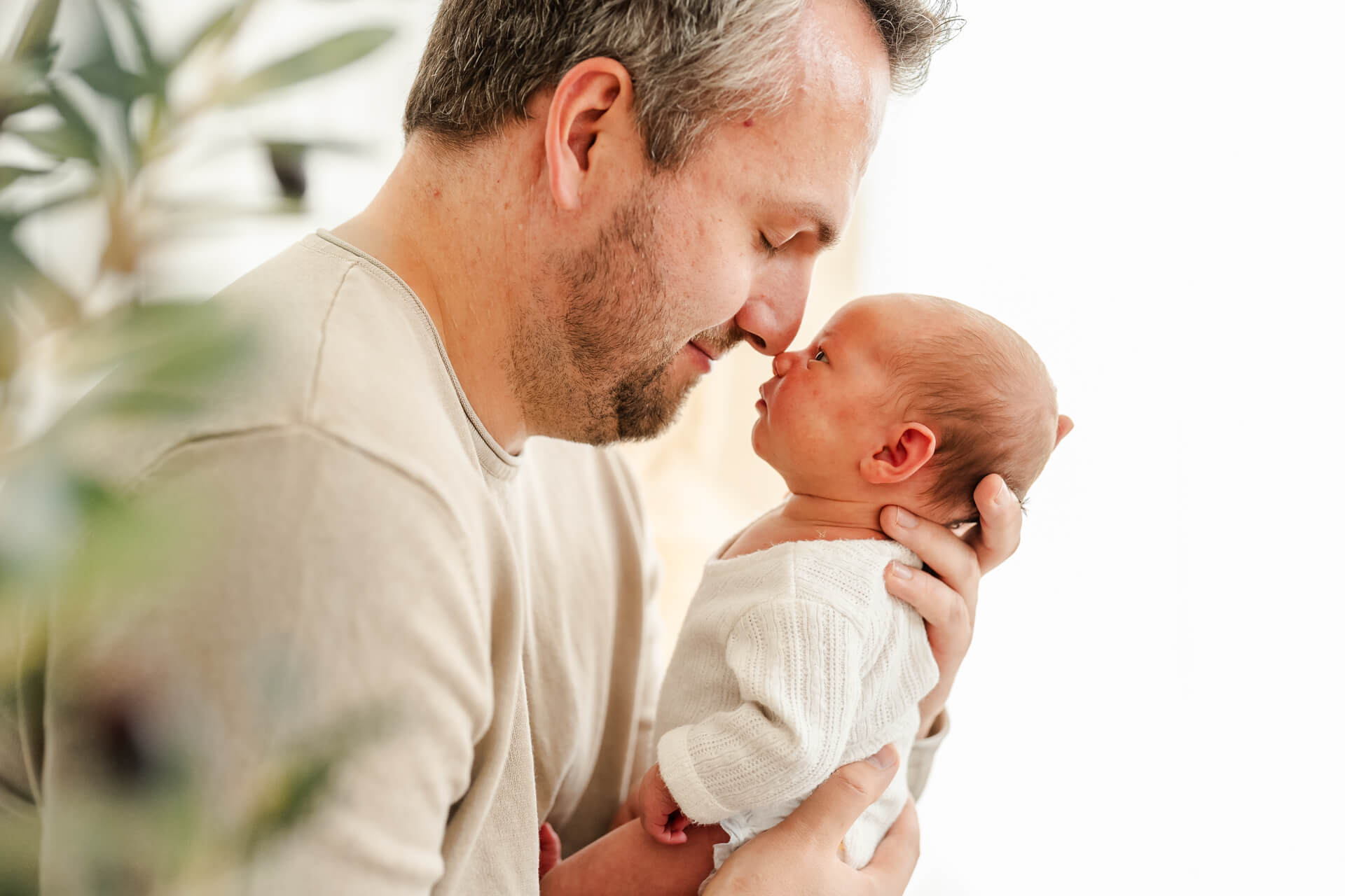 Papa hält sein Neugeborenes in den Armen und die Nasen der beiden berühren sich