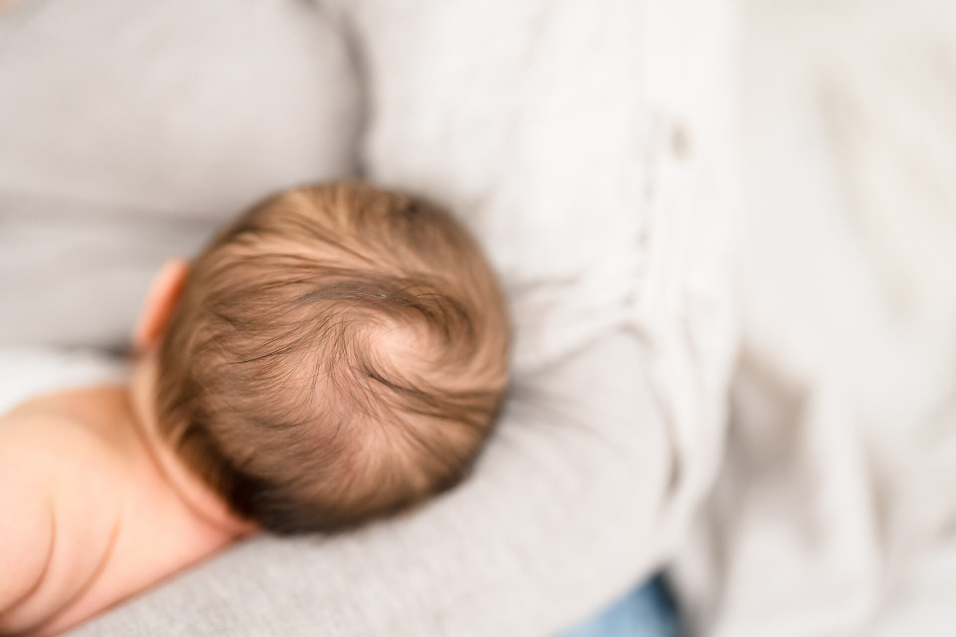 Neugeborenes ist von hinten zu sehen, nur der Kopf mit den weichen Babyhaaren
