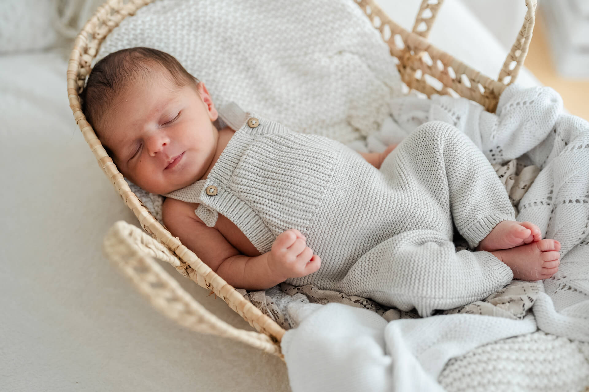 schlafendes Neugeborenes liegt eingekuschelt in einem Körbchen