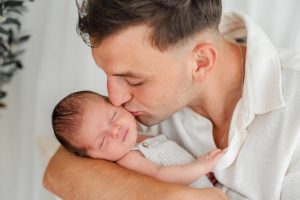 Papa hält sein kleines Baby und gibt ihm einen Kuss auf die Wange