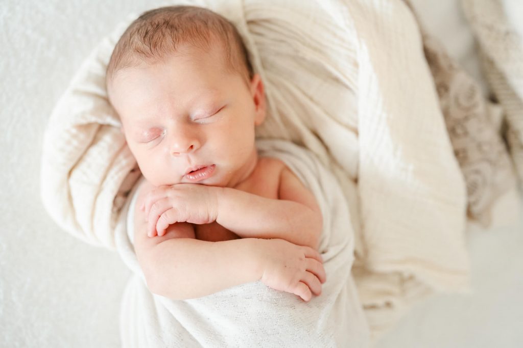 schlafendes Neugeborenes leigt eingekuschelt in weichen Decken