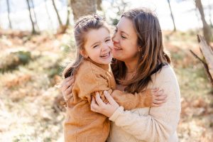 Mama und Tochter umarmen sich und lachen sich an, in der Natur
